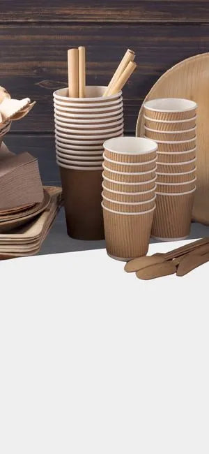 Nachhaltiges Einweggeschirr aus Pappe mit Bechern, Tellern, Schalen, Holzbesteck und Rührstäbchen auf Holzhintergrund.