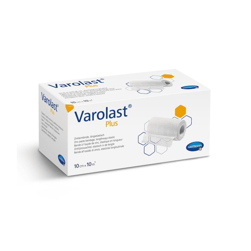 Op de afbeelding is een rechthoekige witte doos te zien met Hartmann Varolast® Plus zink-lijmverband. Op de verpakking staat een afbeelding van een opgerold verband en zeshoekige motieven. Ideaal voor de behandeling van oedeem en flebitis; de afmetingen die op de doos staan vermeld, zijn 10 cm x 10 m. Rechtsonder is het logo van Paul Hartmann AG te zien.