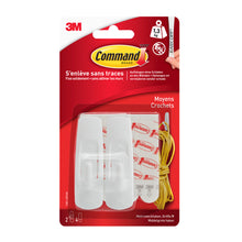 Eine klare Blisterpackung 3M Deutschland GmbH Mittelgroße Command™ Mehrzweckhaken M im Vorteilspack, 17001-2, enthält zwei weiße Haken, vier Klebestreifen, gelbe Kordel und mehrsprachige Infos für beschädigungsfreie Befestigung.