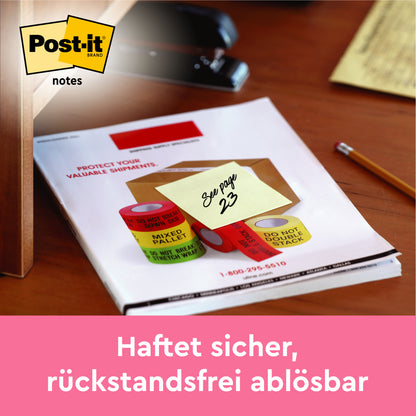 Eine Post-it® Note, Gelb, 76x76 mm, 100 Blatt/Block (2 Blöcke/Packung), von 3M Deutschland GmbH, mit "Siehe Seite 23" liegt auf einem Schreibtisch. Darunter steht auf Deutsch: "Haftet sicher, rückstandsfrei ablösbar.
