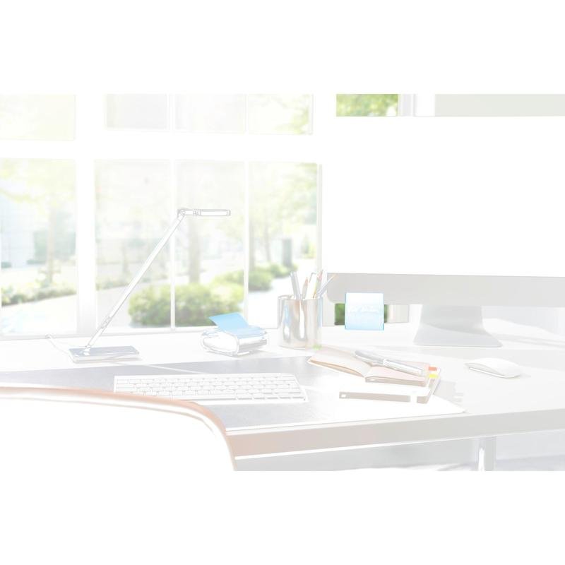 Een moderne bureaustelling met een 3M Post-it® Z-Notes Dispenser PRO in zwart met gele Post-it® Super Sticky Z-Notes (76x76 mm, 90 vellen/blok), notitieboeken, pennen en een lamp voor grote ramen met zonlicht en groene bomen buiten.