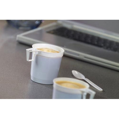 Twee Starpak koffiekopjes (0,25 l, wit, PS) uit de verpakking van 40 staan gevuld op grijs; daarnaast een witte plastic lepel en op de achtergrond een laptoptoetsenbord als hint naar dagelijks koffiegenot.