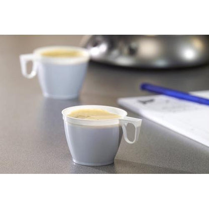 Twee kleine Starpak koffiekopjes (PS, 0,18l, Ø7,8cm, wit) uit een set van 10 staan gevuld met koffie op een grijze ondergrond, op de achtergrond zijn een blauwe pen en een onscherp wit vel papier te zien.