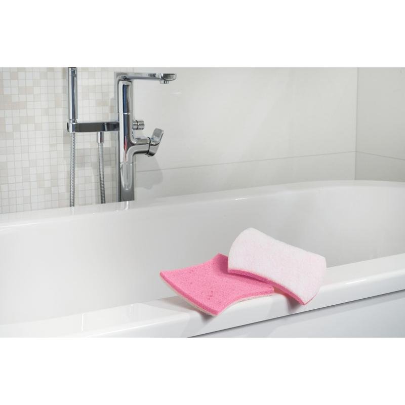 Te zien is een wit bad met verchroomde kranen. Op de rand bevinden zich een roze badkamerspons en een Scotch-Brite® Bath XXL reinigingsspons voor de badkamer van 3M Deutschland GmbH. De achtergrond toont witte tegels met een mozaïekpatroon.
