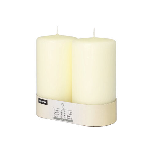 Twee Starpak stompkaarsen Ø 80 mm met platte kop staan in een eenvoudige kartonnen houder met etiket – een vleugje tijdloze elegantie voor elke ambiance.