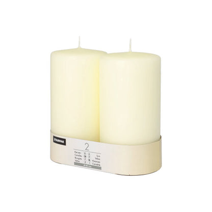 Twee Starpak stompkaarsen Ø 80 mm met platte kop staan in een eenvoudige kartonnen houder met etiket – een vleugje tijdloze elegantie voor elke ambiance.
