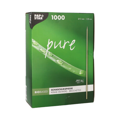 Een groene doos met het opschrift "PAPSTAR schaschlikspiesen hout pure" (Ø 3 mm, 20 cm, 1000 stuks) van PAPSTAR GmbH toont een spies en de close-up van een dauwverse groene plant.
