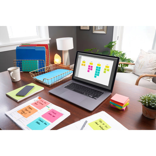 Ein aufgeräumter Home-Office-Schreibtisch mit Laptop und digitalem Kalender, bunten Ordnern, Smartphone, Notizbüchern, 3M Deutschland GmbH Post-it® Notes Poptimistic Collection (38 mm x 51 mm), Stift, kleiner Pflanze und Lampe in hellem Tageslicht.