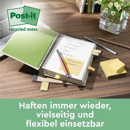 Op een bureau liggen een Post-it® Recycling Z-Notes Blok (76x76mm, 100 vel, 100% PEFC) van 3M Deutschland GmbH, plaknotities in een geopend notitieboek, een pen, verspreide notities, een glas water en een potplant. "Plakken keer op keer - veelzijdig & flexibel."