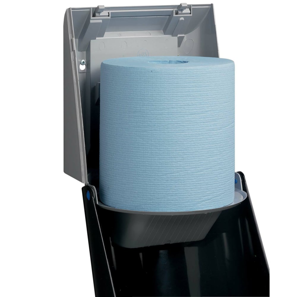 Een close-up van een Kimberly-Clark Professional™ doekjesdispenser - centrale uitgifte / grijs toont de geopende dispenser met een grote blauwe rol, die een hygiënische doekjesuitgifte mogelijk maakt. Van Kimberly-Clark GmbH.
