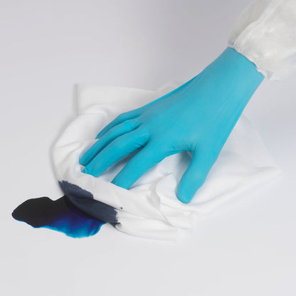 Een persoon met een blauwe handschoen veegt met een Kimtech® Polyester Vlakdoek (Wit, Groot, 8x50 vellen) van Kimberly-Clark GmbH een donkerblauwe vloeistof op een wit oppervlak op.