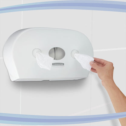 Een hand trekt tissues uit een Kimberly-Clark GmbH Aquarius™ toiletpapierdispenser - centrale afname / wit / Jumbo, die is uitgerust met twee rollen en aan een betegelde muur is gemonteerd.