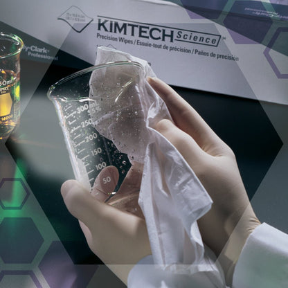Een gehandschoende hand veegt een bekerglas af met een wit doekje naast een doos Kimtech® Science Precisiedoekjes van Kimberly-Clark GmbH (Groot, Wit, 15x196 doekjes). Op de achtergrond zijn laboratoriumapparatuur en andere laboratoriumdoekjes te zien.