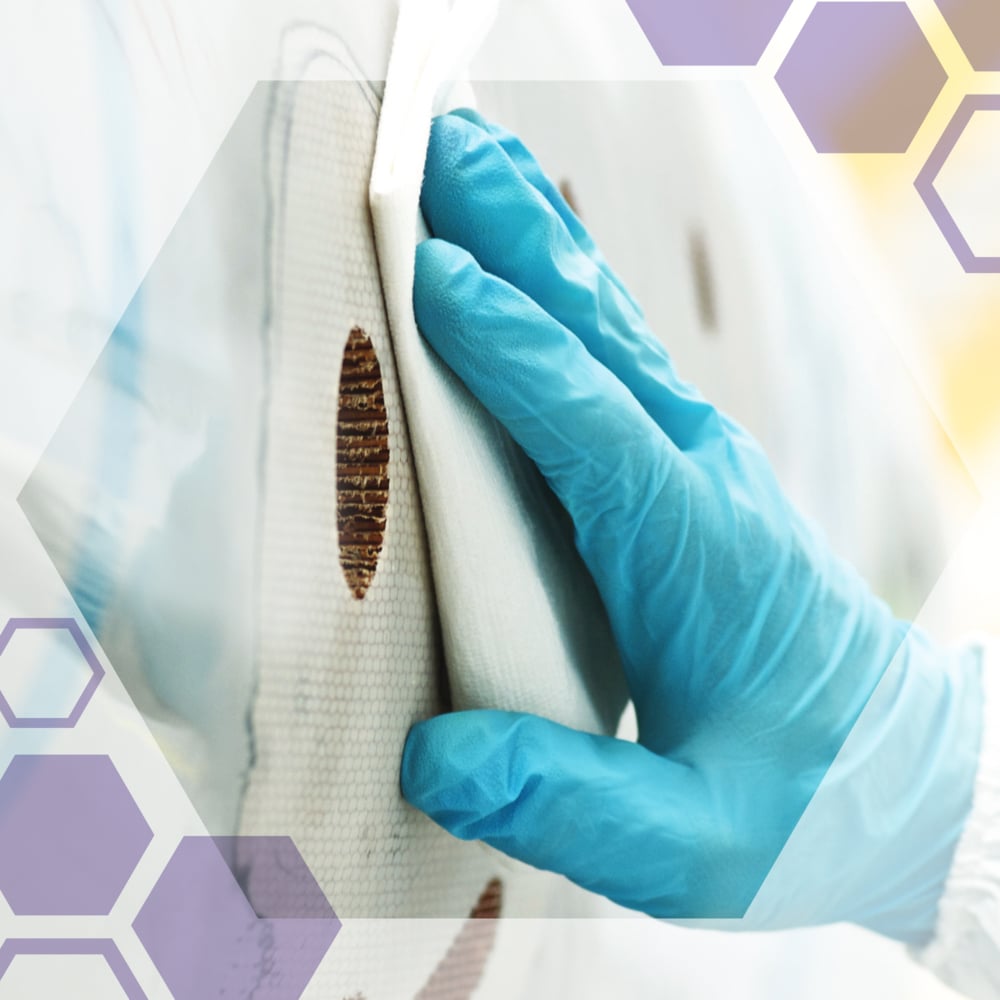 Een gehandschoende hand reinigt een wit oppervlak met bruine vlekken met Kimtech® Science Precisiedoekjes (Klein, 30 x 286) van Kimberly-Clark GmbH. Halftransparante zeshoeken benadrukken deze pluisvrije doekjes, die ideaal zijn voor reiniging in het laboratorium.