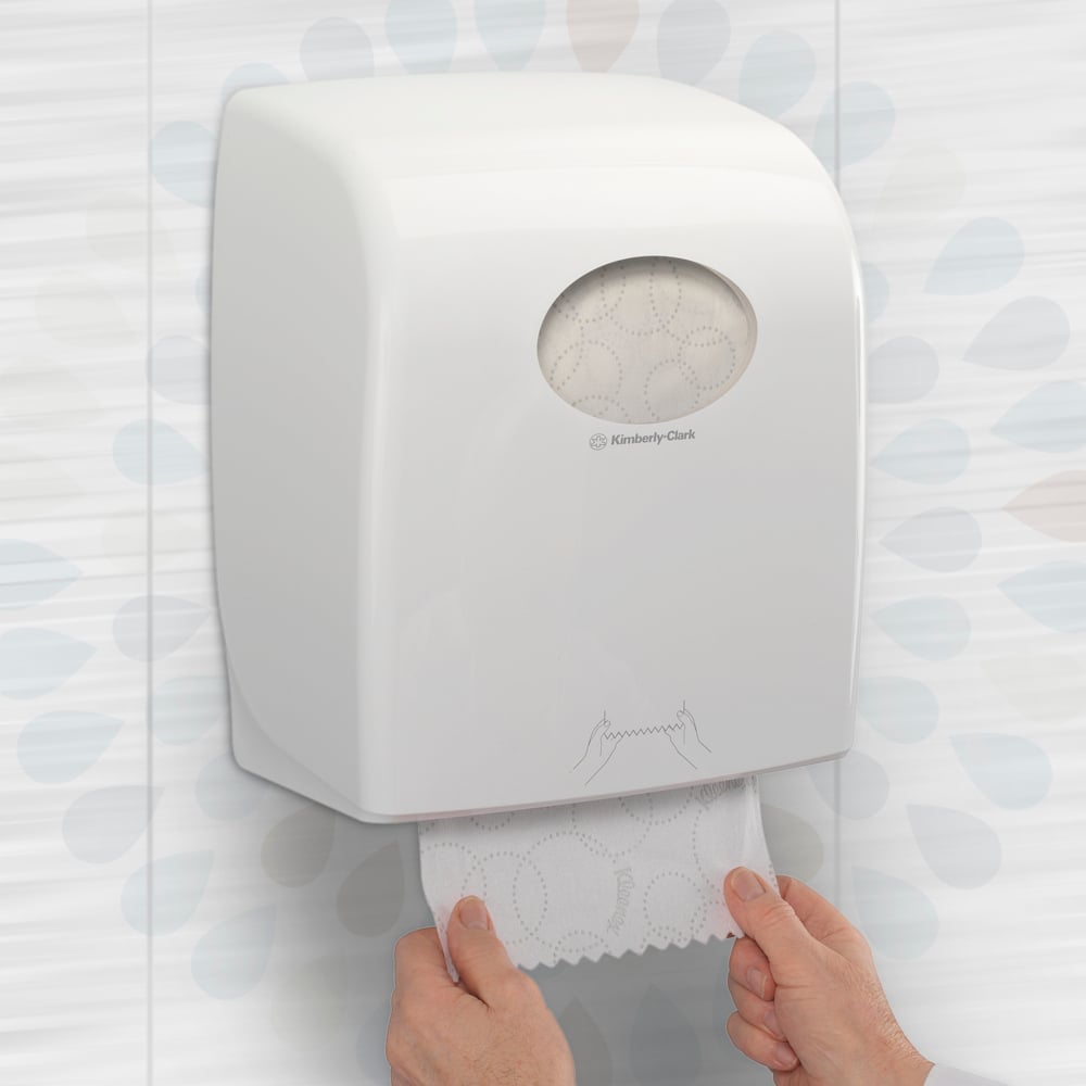 Een persoon trekt een Kleenex® ULTRA™ handdoeken-rol (wit, 150m) van Kimberly-Clark GmbH uit een muurlader in een toilet en zorgt zo voor hygiënisch handen drogen. Verpakking: 6 rollen/doos.