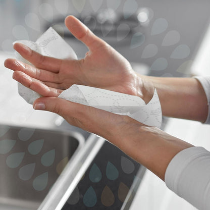 Een persoon droogt zijn handen boven een gootsteen met een witte 2-laagse Kleenex® Ultra™ Rollenhanddoek E-roll Slimroll™ van Kimberly-Clark GmbH. Waterdruppelvormen overlappen de afbeelding voor een halftransparant effect.