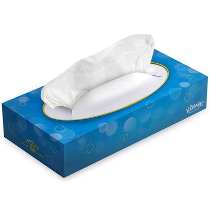 Eine rechteckige blaue Schachtel mit Kleenex® Kosmetiktüchern - Standard / Weiß von Kimberly-Clark GmbH, mit einem Taschentuch, das aus der oberen ovalen Öffnung gezogen wird. Die Schachtel hat ein Blasenmuster und ein Kleenex-Logo - ideal für die Gesichtsreinigung oder zum Abschminken.