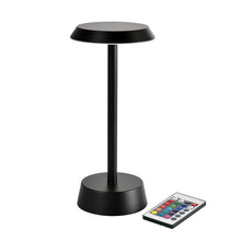 De NOUR Draadloze LED-lamp in grafiet van Duni GmbH, met modern ontwerp en ronde voet, wordt naast een afstandsbediening met kleurrijke knoppen getoond - perfect voor uw woonkamerdecoratie.