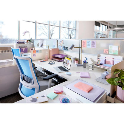 Een modern kantoor met witte bureaus, blauwe stoelen, een laptop, planten en de Post-it® Super Sticky Z-Notes Boost Collection van 3M Deutschland GmbH (76x76 mm, 90 vel/Block, 100% PEFC). Grote ramen bieden natuurlijk licht en uitzicht op bomen.