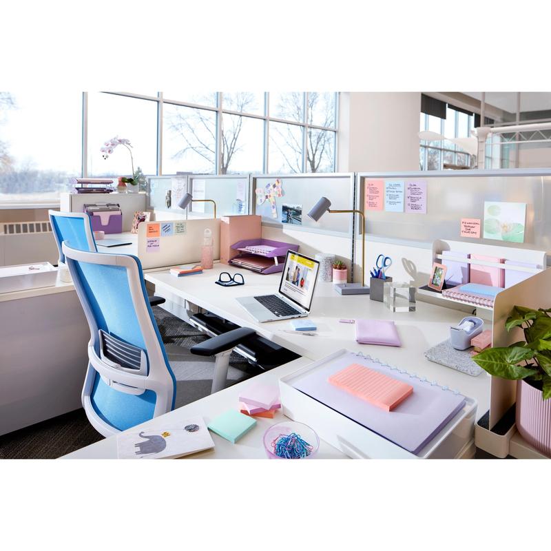 Een moderne werkplek met witte bureaus, blauwe stoelen, laptops, kantoormateriaal, kamerplanten en natuurlijk licht toont Post-it® Super Sticky Notes (76 mm x 127 mm, 90 vel/blok, 100% PEFC) van 3M Deutschland GmbH.