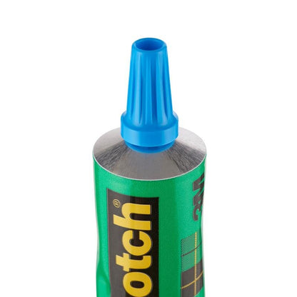Close-up van een rechtopstaande groene 30-ml-tube met de tekst "Scotch® transparante oplosmiddelvrije lijm voor huishoudelijk gebruik" van 3M Deutschland GmbH, met zwart-geel logo en blauwe kunststof dop.