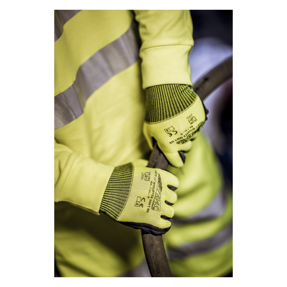 Eine Person, die eine gelbe Warnweste und Nylonhandschuhe NITRAS NYLOTEX SOFT HV von AS Arbeitsschutz GmbH, neongelb, teilbeschichtet – mit schwarzem Text und Sicherheitssymbolen – trägt, hält ein dickes, dunkles Kabel oder einen Schlauch.