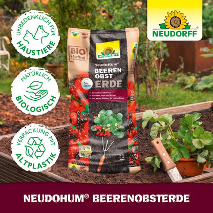 Een zak NeudoHum BeerenobstErde uit de Neudorff Shop ligt op een verhoogd bed met aardbeien en een schep; milieuvriendelijke en huisdiervriendelijke symbolen tonen aan dat het ideaal is voor fruit in pot of op het balkon.
