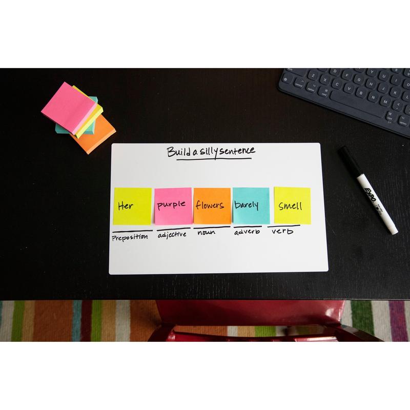 Op een zwart bureau staat een whiteboard met de tekst "Build a silly sentence". De Post-it® Notes kubus, Ultra-kleuren, 76x76 mm, van 3M Nederland B.V. tonen de woordsoorten. Verder op het bureau: een droog uitwisbare marker, een notitieblok en een toetsenbord.