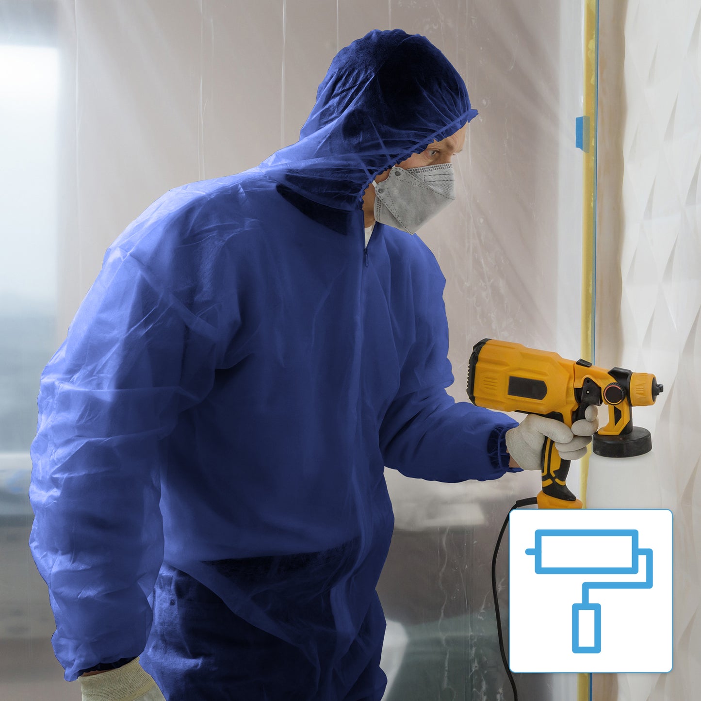 Een persoon die de ARNOMED COVER PP-OVERALL XTRA STRONG wegwerpoverall met capuchon in blauw van ARNOWA GmbH, handschoenen en een gezichtsmasker draagt, gebruikt binnenshuis een geel verfspuitapparaat. Een deel van de werkruimte is bedekt met een plastic folie. Een verfroller-symbool is zichtbaar.