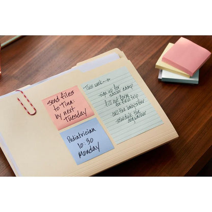 Op een houten bureau ligt een map met blauwe, roze en gele Post-it® Recycling Z-Notes (76 mm x 76 mm, 100 vel/Blok, 100% PEFC) van 3M Deutschland GmbH met handgeschreven herinneringen. Kleurrijke, ongebruikte notities zijn ernaast gestapeld.