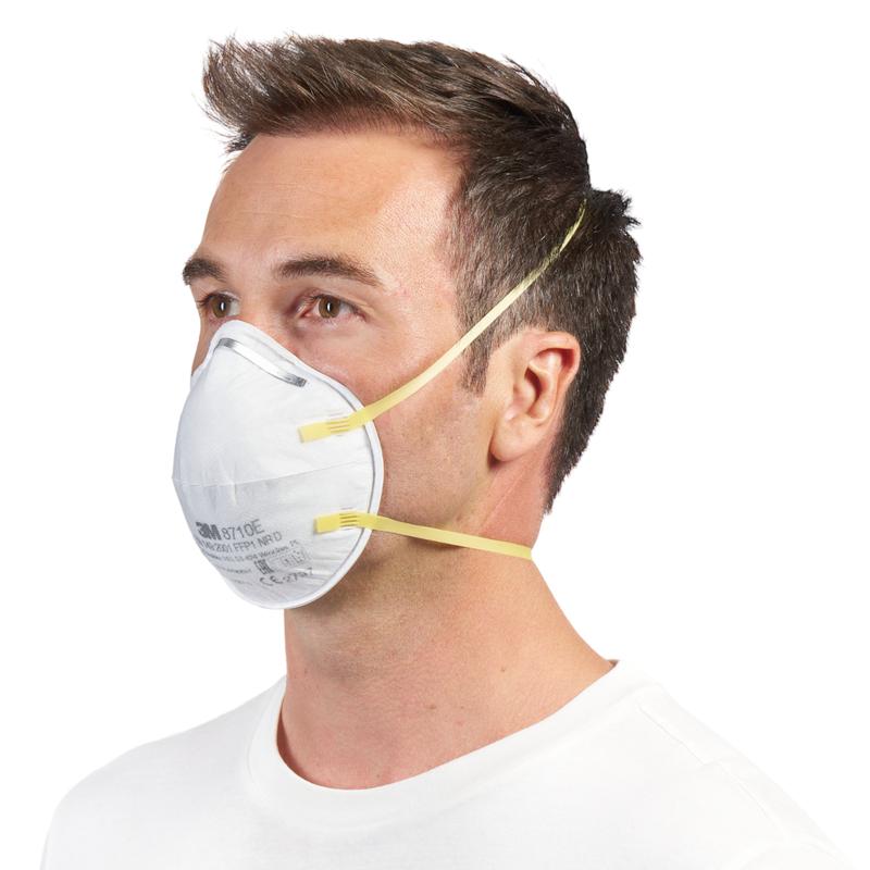 Een man met kort bruin haar draagt een 3M™ deeltjesmasker 8710E FFP1 (van 3M Deutschland GmbH) met gele banden en zonder ventiel over neus en mond, gecombineerd met een eenvoudig wit overhemd tegen een witte achtergrond.