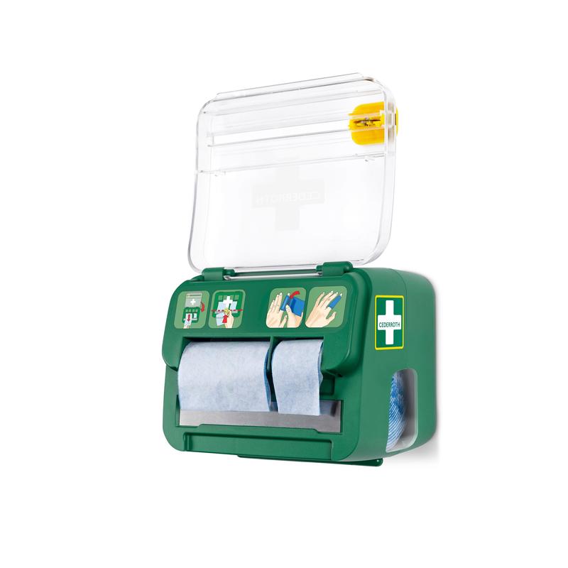 De groene, aan de muur gemonteerde Cederroth schuimverband 2-in-1 dispenser van Orkla Wound Care AB bevat zes verbanden, heeft een transparant deksel met kruissymbool, blauwe papierrollen, een geïllustreerde handleiding en een geel gereedschap voor noodwondverzorging aan de bovenkant.