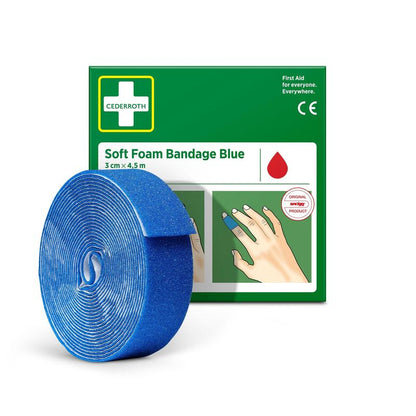Een rol Cederroth Soft Foam Binde blauw 3x450cm van Orkla Wound Care AB is afgebeeld voor de groen-witte verpakking, waarop de blauwe zwachtel om een vinger is gewikkeld.
