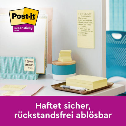 Een werkruimte met Post-it® Super Sticky Notes, 76 mm x 76 mm, 90 vel/blok van 3M Deutschland GmbH op het bureau en aan de muur met notitieboeken, pen en mappen. Onderaan de tekst in het Duits: "Hecht veilig, residuvrij verwijderbaar."