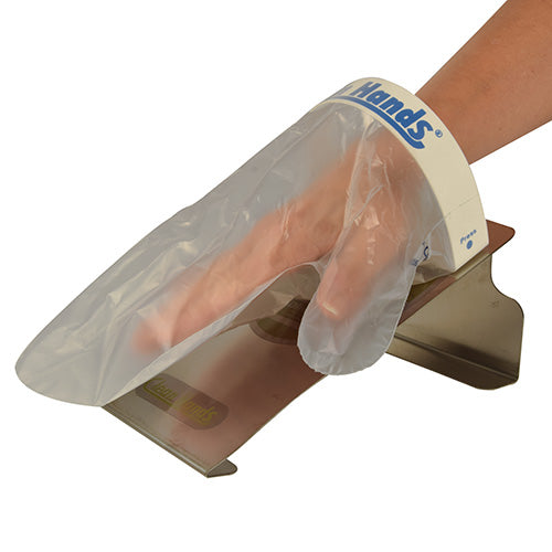 Een hand draagt een wegwerpkunststofhandschoen uit de PAPSTAR Clean Hands Base Kit (roestvrij staal, 11,5x12,7x22 cm, zilver), die op de manchet is gemarkeerd met "Clean Hands" voor hygiënische reinheid. De handschoen wordt uit een door de PAPSTAR GmbH gemonteerde doos (1 stuk) gehaald.