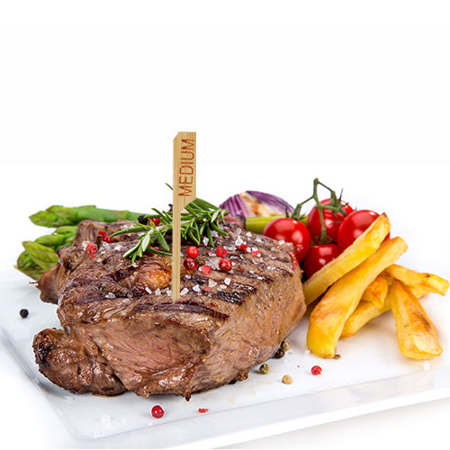 Ein gegrilltes Steak mit der Bezeichnung „medium“ und dem PAPSTAR 250 Steak-Marker 9 cm der PAPSTAR GmbH wird auf einem weißen Teller mit Pommes Frites, Spargel, Kirschtomaten, roten Zwiebeln und Kräutern serviert – perfekt für die professionelle Restaurantküche.
