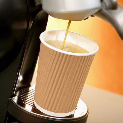 Een PAPSTAR GmbH Ripple Wall kartonnen drinkbeker (Ø 9 cm, 13,7 cm hoog) wordt gevuld met koffie terwijl hij op een koffiemachine staat.