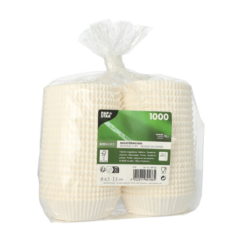 Een doorzichtige kunststofverpakking bevat vier stapels papieren bakvormpjes "PAPSTAR 1000 bakvormpjes rond" van PAPSTAR GmbH met een groen etiket, waarop 1000 stuks, informatie over het biobased materiaal en andere productdetails staan.