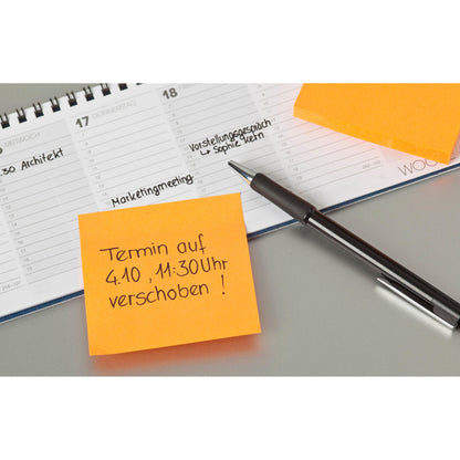 Ein Stift liegt auf einem aufgeschlagenen Planer neben zwei orangefarbenen Post-it® Zetteln (76 mm x 76 mm, 100 Blatt/Block, 100% PEFC) der 3M Deutschland GmbH; ein Zettel verschiebt einen Termin auf den 4. Oktober um 11:30 Uhr in deutscher Sprache. Handschriftliche Einträge erscheinen im Planer.