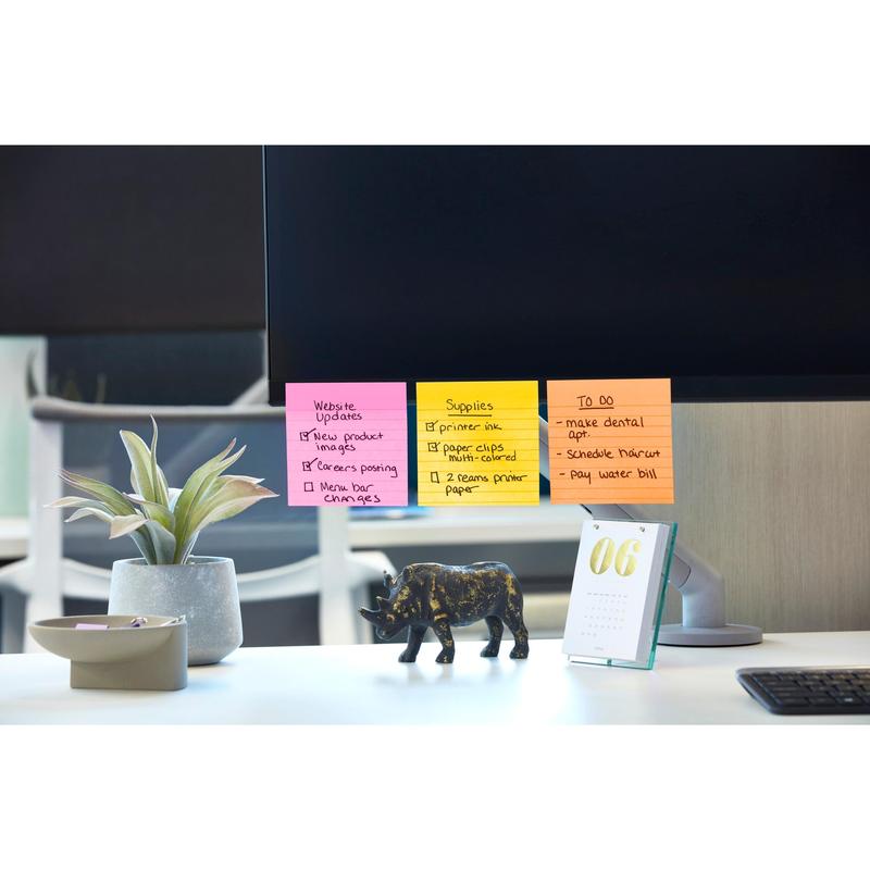 Een computermonitor toont kleurrijke Post-it® Super Sticky Notes in groot formaat (101 mm x 101 mm, 90 vel/blok, 100% PEFC) van 3M Deutschland GmbH met website-updates, materiaal en taken. Op het bureau staan een plant, een zwarte olifantenfiguur en een tafelkalender met het jaartal "06".