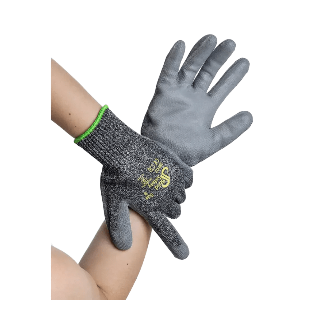 Twee handen dragen AMPri SolidSafety Cut High snijbestendige handschoenen, grijze werkhandschoenen van snijbestendig materiaal. Deze handschoenen van AMPri Handelsgesellschaft mbH hebben een gestructureerd oppervlak met geel-witte tekst op de achterkant en een groene rand bij de pols, die zowel duurzaamheid als bescherming biedt.