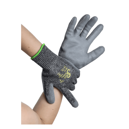 Twee handen dragen AMPri SolidSafety Cut High snijbestendige handschoenen, grijze werkhandschoenen van snijbestendig materiaal. Deze handschoenen van AMPri Handelsgesellschaft mbH hebben een gestructureerd oppervlak met geel-witte tekst op de achterkant en een groene rand bij de pols, die zowel duurzaamheid als bescherming biedt.