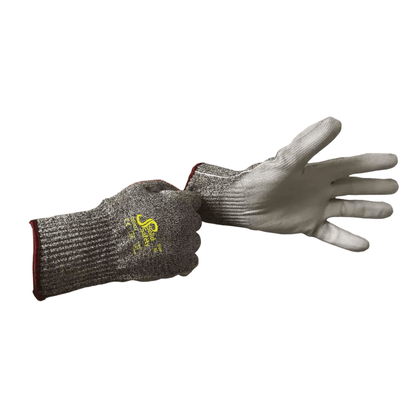 Een persoon draagt aan de linkerhand een AMPri SolidSafety Cut High snijbestendige handschoen van snijbestendige materialen, terwijl de rechterhand de pols van een tweede handschoen vasthoudt. Deze grijze handschoenen van AMPri Handelsgesellschaft mbH zijn gemaakt van HPPE-garen met een geel logo op de achterkant, een geribbelde textuur en een rode rand aan de manchet.