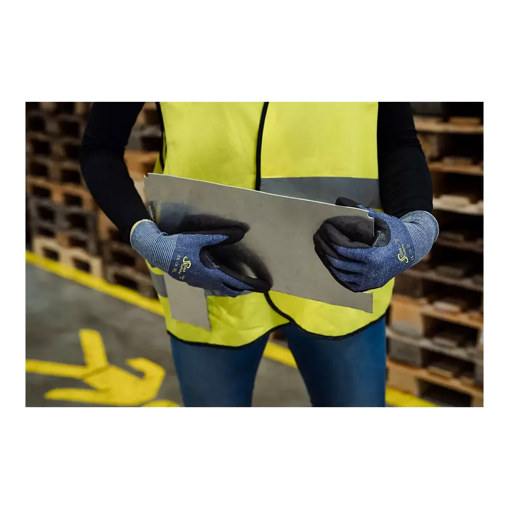 Een persoon met een neongeel veiligheidsvest en blauwe AMPri SolidSafety Cut snijbestendige handschoenen S - XXL van AMPri Handelsgesellschaft mbH hanteert voorzichtig een grote metalen plaat in het magazijn. Op de achtergrond zijn houten pallets gestapeld, gele markeringen op de vloer leiden veilige bewegingen en benadrukken de arbeidsveiligheid.