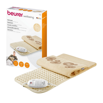 Afbeelding van een Beurer HK 45 verwarmingskussen Cosy-set. De set omvat een crèmekleurig elektrisch verwarmingskussen met gestructureerd oppervlak en aangesloten besturingseenheid. Naast het kussen bevindt zich de verpakkingsdoos van het product met afbeeldingen en beschrijvingen in meerdere talen. Het kussen van de Beurer GmbH voldoet aan de OEKO-TEX® Standard 100-certificering.
