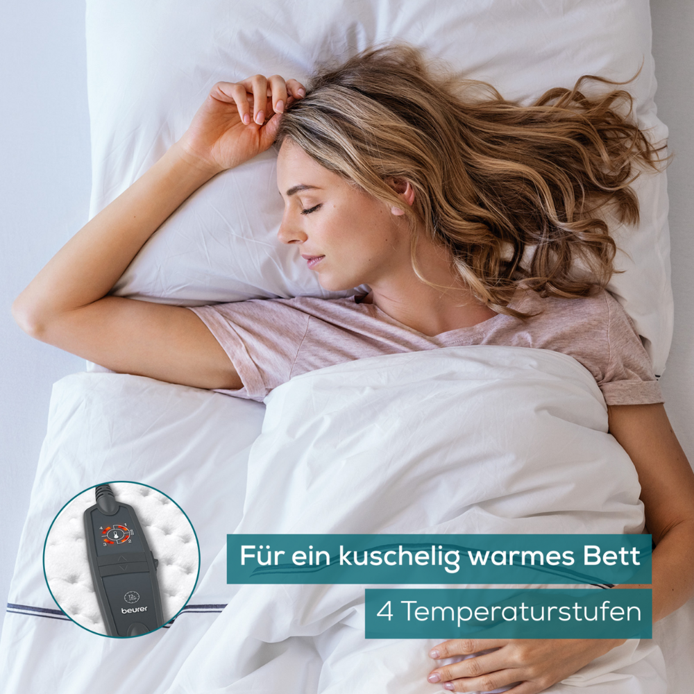 Een vrouw met blond haar slaapt in een bed met wit beddengoed. In een inzetstuk is een donkergekleurd elektronisch apparaat met knoppen te zien, waarschijnlijk een Beurer warmteonderdeken UB 60 Green Planet-bediening voor een elektrische deken van de Beurer GmbH. De Duitse tekst luidt: "Voor een gezellig warm bed" en "4 temperatuurstanden."
