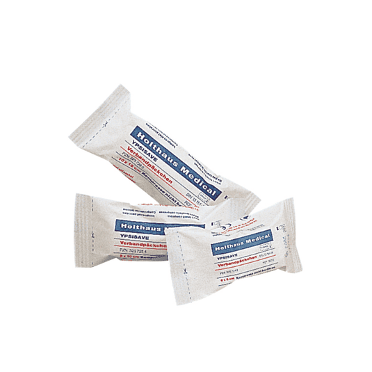 Er worden drie verpakkingen Holthaus Medical YPSISAVE-verbandpakketjes tentoongesteld, steriel, elk met blauwe en rode opschriften. De tekst op de verpakking is vermoedelijk in het Duits en bevat productinformatie. Elk pakketje is afzonderlijk verpakt en verzegeld, wat erop wijst dat het om steriele verbandpakketjes van Holthaus Medical GmbH & Co. KG gaat.