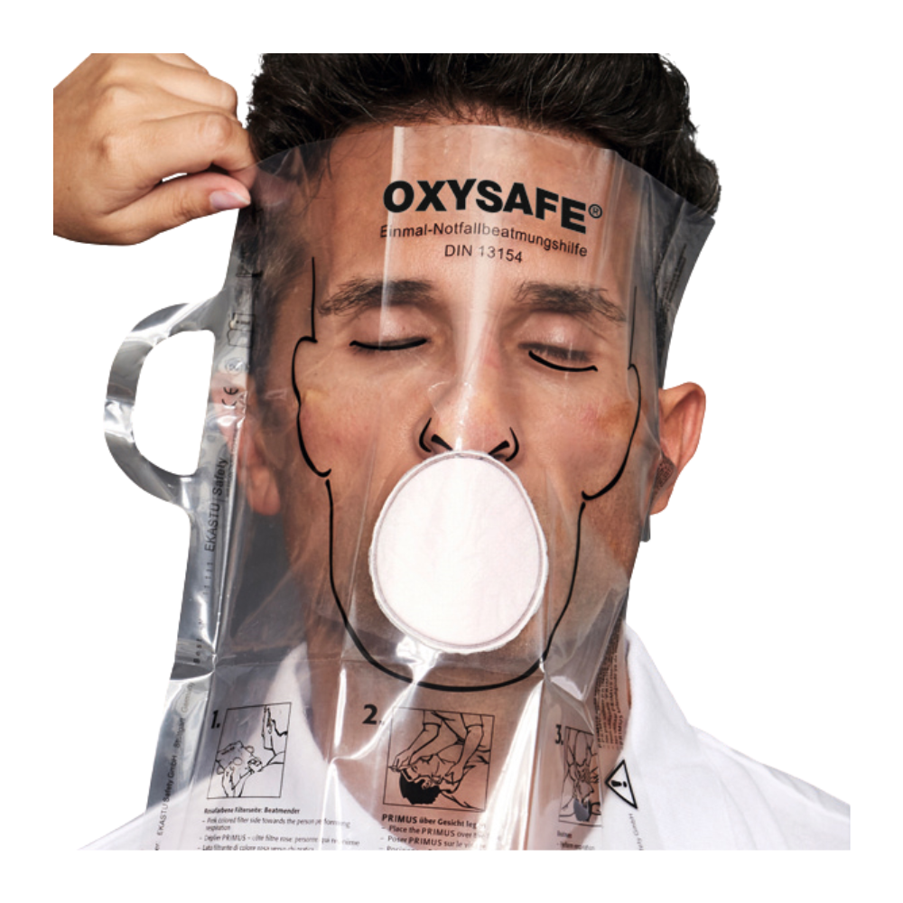 Een persoon draagt een transparant Holthaus Oxysafe® noodbeademingsmasker van Holthaus Medical GmbH & Co. KG en heeft de ogen gesloten, terwijl een andere persoon het masker aanpast. Het product is voorzien van instructies en diagrammen die op het kunststof oppervlak zijn gedrukt.