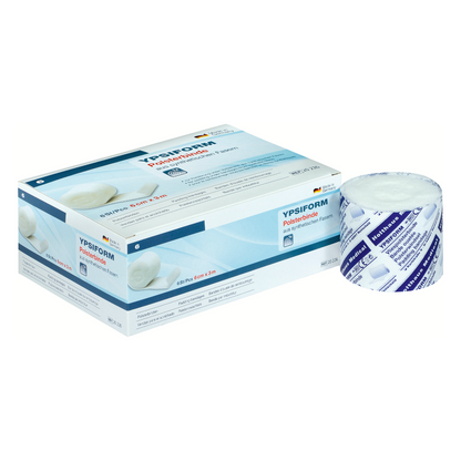 Een doos Holthaus Ypsiform Polsterbinde is afgebeeld naast een onverpakte rol van het verband. De verpakking is overwegend wit met blauwe accenten en tekst, inclusief productdetails en het handelsmerk van Holthaus Medical GmbH & Co. KG. Deze hoogwaardige polsterbinde biedt een uitstekende onderlaag voor verschillende medische doeleinden.