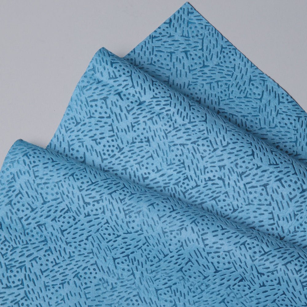 Close-up van gevouwen Kimtech® procesreinigingsdoeken (Kimberly-Clark GmbH) in blauw, BRAG™ Box - 160 vellen, met geometrisch streep- en stippenpatroon. Ideaal voor veeleisende industriële reiniging. Uitgestald op een lichtgrijze ondergrond.